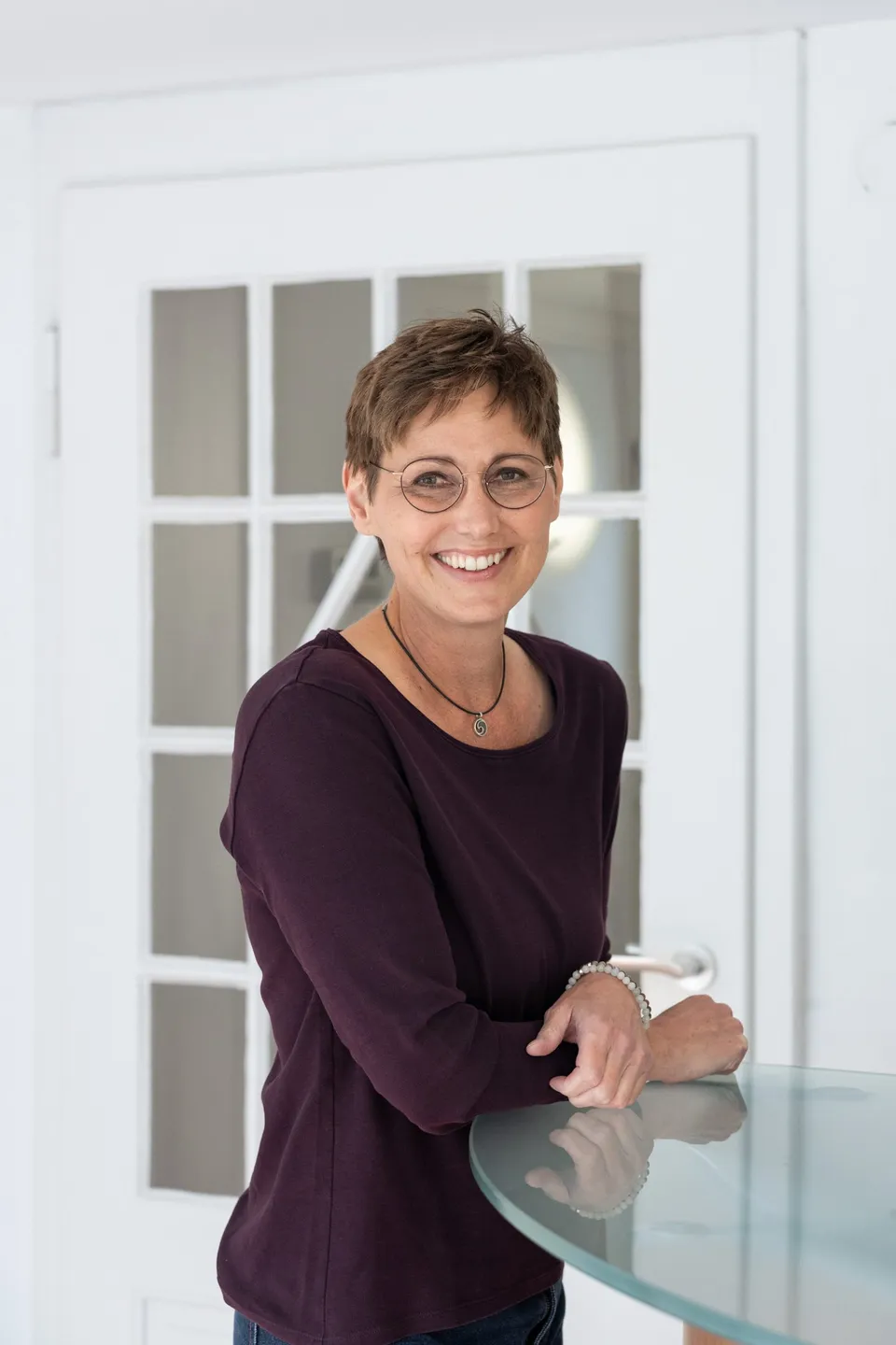 Stefanie Wöhrle lächelnd an einem Glastisch in ihrer Praxis